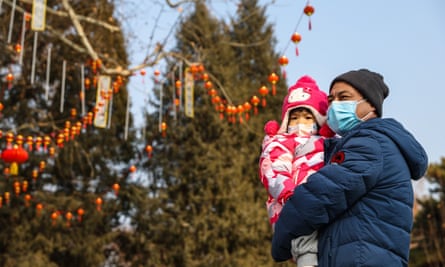 A man and a child wearing a face mask walk in a park in Beijing, China, ahead of the Chinese lunar new year