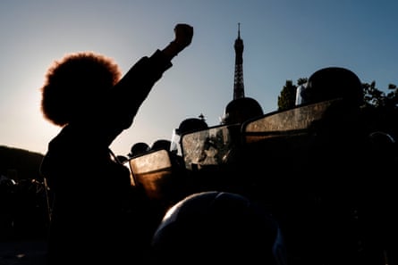 People raise their fists in front of riot policemen during a protest at the Champ de Mars, with the Eiffel Tower in background, in Paris in June 2020.