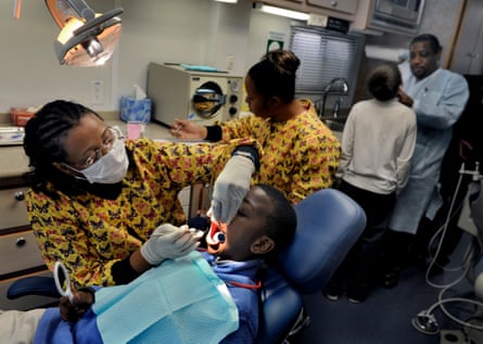 Dr Belinda Carver-Taylor (left) cleans a child’s teeth inside her mobile surgery, The Deamonte Driver Dental Project.