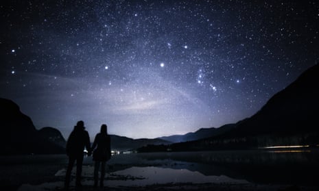 A couple look up at the night sky where Orion’s belt is clearly seen.