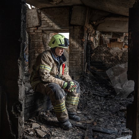 A firefighter sits in contemplation in the ruins of a building