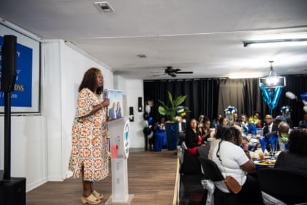 a person at a small podium speaks to attendees at an event for voters