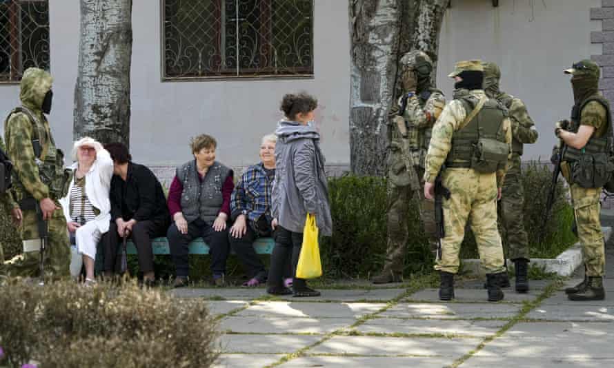 Elderly local residents speak to a group of Russian soldiers in Kherson.
