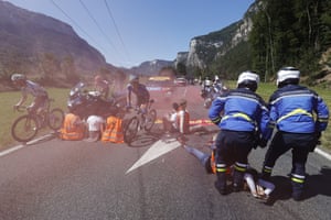 Stage 10 Morzine to Megeve Lennard Kamna (left) of Bora Hansgrohe and Kristian Sbaragli (centre) of Alpecin Deceuninck pass by environmental protesters sitting on the road as police attempt to remove them