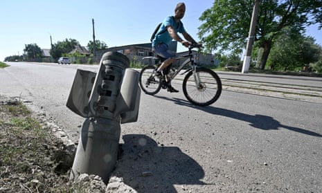 A cyclist rides past a tail section of a rocket embedded in a road in Kramatorsk.