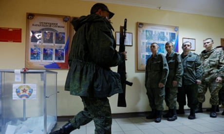 A military member of the self-proclaimed Luhansk People's Republic walks with a firearm as others queue during the so-called ‘referendums’ in Ukraine