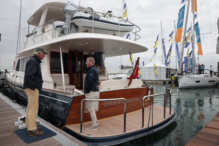 Two men look at a boat tied to a pontoon