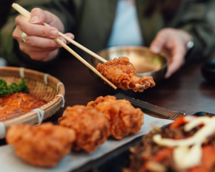 Cropped changeable of a female eating Korean fried chickenhearted utilizing chopsticks