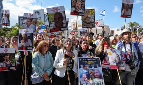 A crowd of people holding signs with the message 'Bring them home'