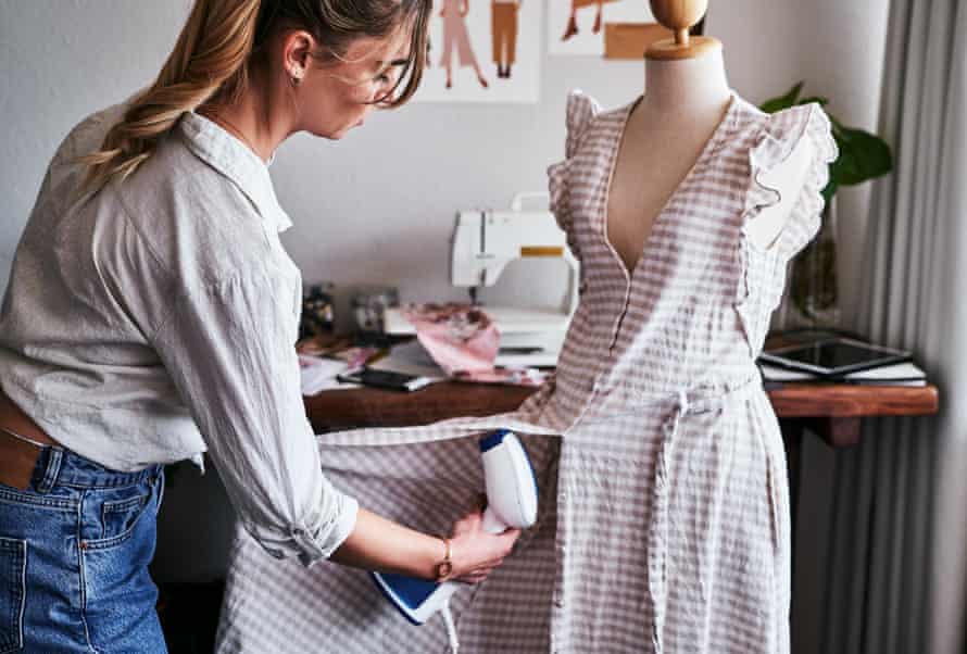 Une femme cuit une robe sur un mannequin.