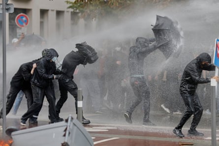 Protesters in black try to shield themselves from sprays of water
