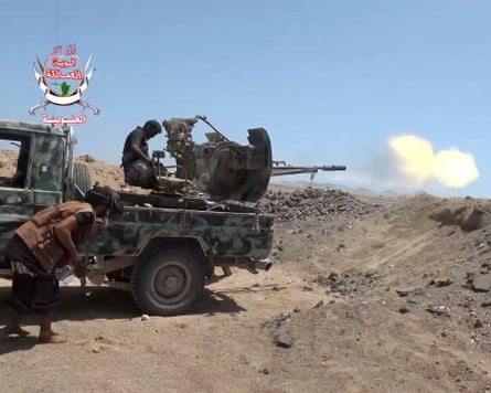 A fighter fires an artillery gun mounted on a truck in a desert landscape.
