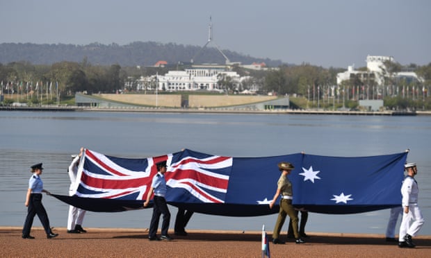 Defence force personnel march with the Australian flag during an Australia Day citizenship ceremony in Canberra earlier this year. 