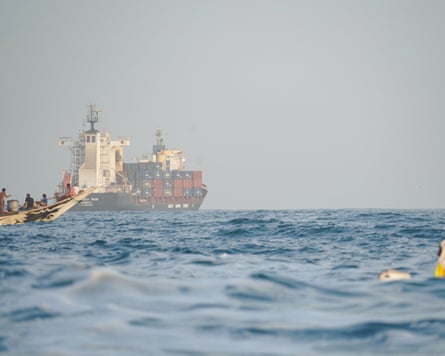 People sail their boats past container ships anchoring near the strait of Bab al-Mandeb off Yemen’s coast in the Gulf of Aden