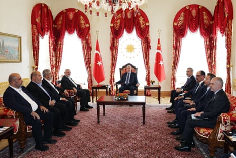 Turkish president Recep Tayyip Erdoğan (C) is pictured sat in a chair with Turkish flags either side of him as he meets Hamas leader Ismail Haniyeh (C-L), along with other Turkish ministers in Istanbul on Saturday.