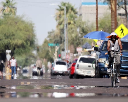A person rides a bicycle as heat waves shimmer from the ground, causing visual distortion
