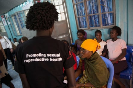 A young woman in a T-short that says Promoting sexual reproductive health talks to a seated older woman 