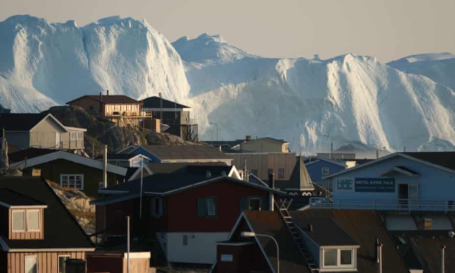 Icebergs loom behind buildings in Ilulissat, Greenland