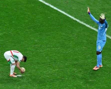 The Morocco forward Brahim Díaz places the ball on the spot in preparation to take a penalty, while the Senegal goalkeeper Édouard Mendy stands over him in an attempt at intimidation