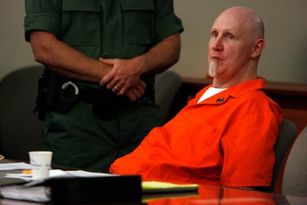 a man in an orange shirt sits at a table