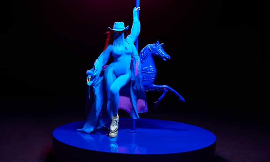 Beyoncé sits on a carousel horse on a stage bathed in blue light.