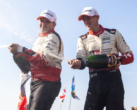 Elfyn Evans (right) sprays onlookers alongside his co-driver Martin Scott after sealing a stunning title win.