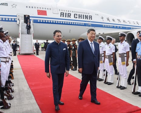 Xi Jinping walking away from an Air China plane along a red carpet.