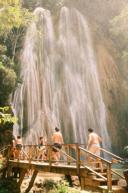 Photograph of people walking across a wooden bridge near a huge waterfall