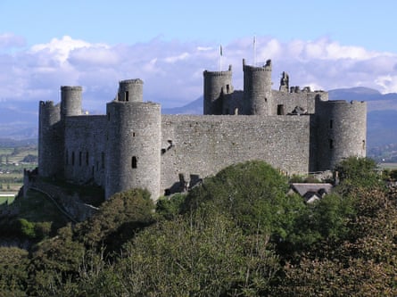 Stone-built castle with towers and turrets and mountains in the backgroung