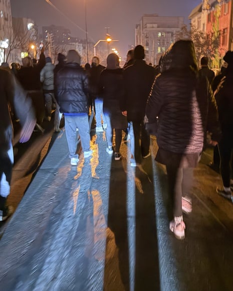 People in silhouette casting shadows walking away from camera in street