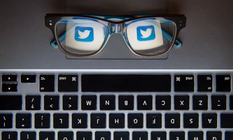 Twitter icon seen through glasses placed on laptop keyboard