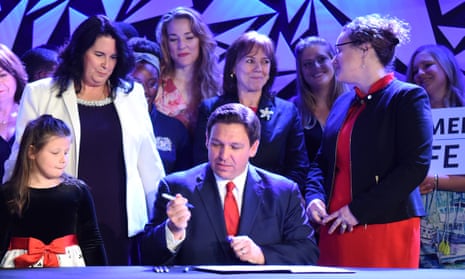 desantis holds pen surrounded by women