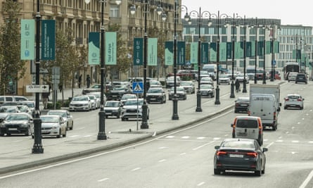 Vehicles drive past Cop29 posters in Baku