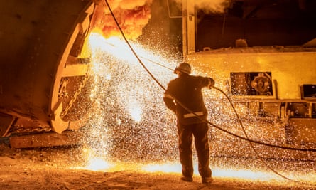 A steelworker cleans the pouring end of a flask