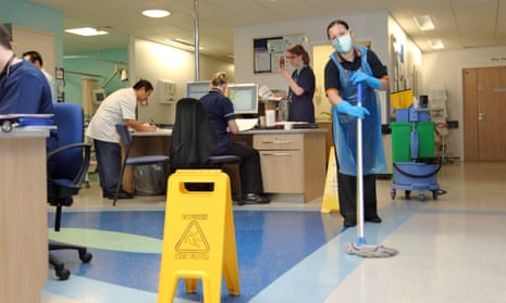 A hospital cleaner wears a protective face mask as she cleans the floor of a busy London hospital ward.