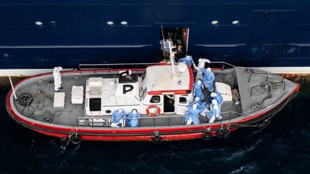 People in hazmat suits on small boat