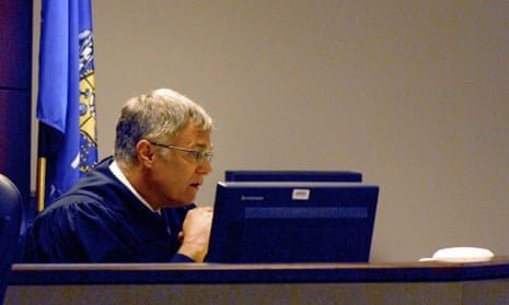 A judge sits at his bench in a courtroom.