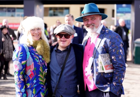 Three racegoers in colourful attire on day at Cheltenham Racecourse.