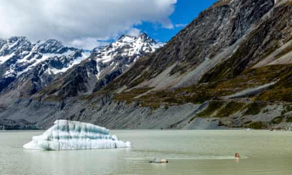A tourist swimming in the glacial Hooker Lake in Aoraki/Mt Cook national park