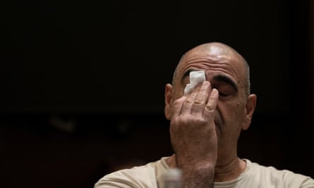 A distraught man with eyes closed holds a tissue.