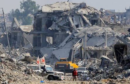 A digger operates in the rubble of demolished buildings