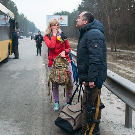 A member of the Territorial Defence unit of Irpin sees off his wife who is leaving on an evacuation bus, 6 March 2022