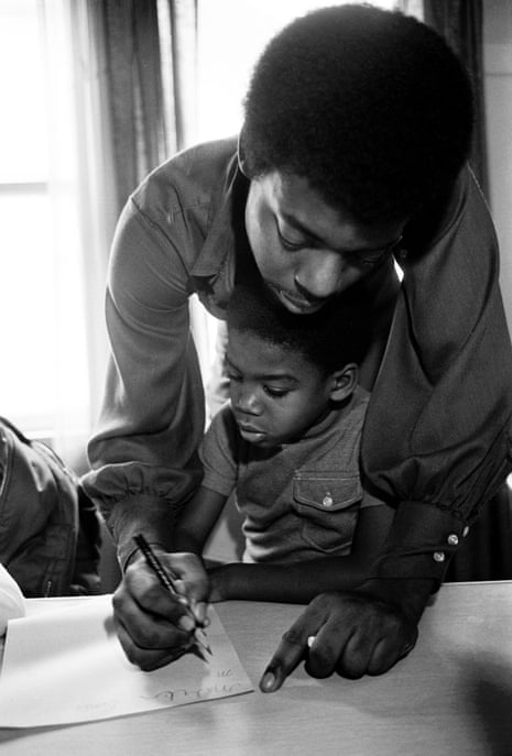 Austin Allen helps Malik Seale, Bobby’s son, write at the Intercommunal Youth Institute in Oakland, in 1972.