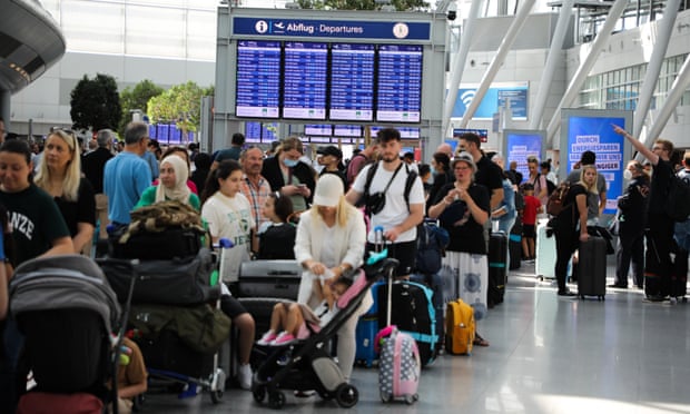 People wait in long lines at Düsseldorf airport on Saturday amid summer travel chaos in Germany