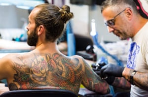 A tattoo artist works on a man’s tattoo International Tattoo Festival, London