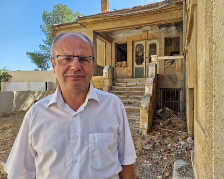 Sami Özuslu standing against a dilapidated stone house