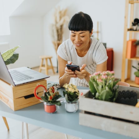 Japanese female florist receiving orders via smartphone in her home shop