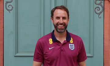 Gareth Southgate smiles and stands in front of a door