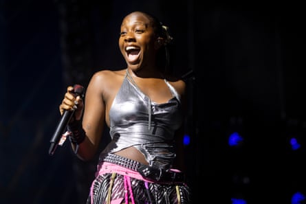 A woman of colour wearing a silver slinky halter-neck top and a pink skirt with fringes