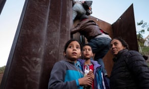 Central American migrants hesitate as others climb the Mexico-US border fence in an attempt to cross to San Diego county, in Playas de Tijuana, Baja California state, Mexico. 6000.jpg?width=300&quality=85&auto=forma